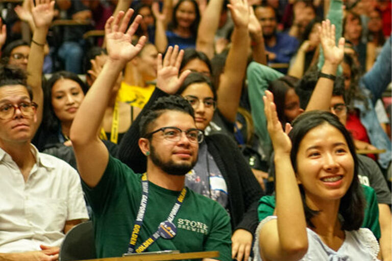 incoming students raising their hands at a lecture 