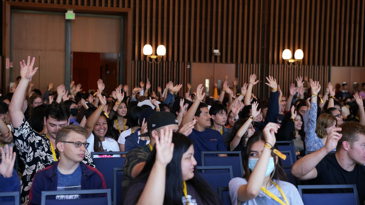Students raising hands in an auditorium